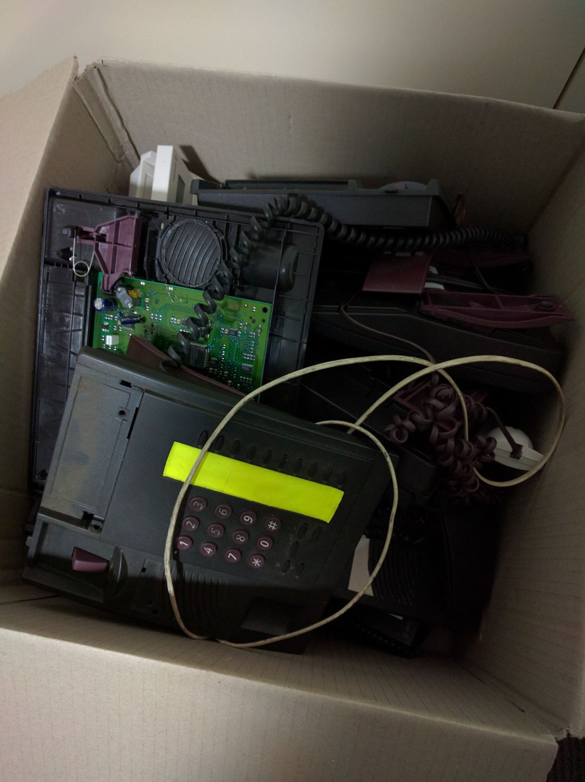 A cardboard box containing old phones with LCD screens